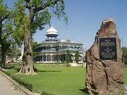 Ornate blue-and-white building, with plaque on a rock in the foreground