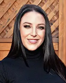 Portrait of a smiling woman with shoulder-length dark hair, wearing a black turtleneck