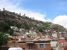 a high stone outcropping with scattered brick houses at the base