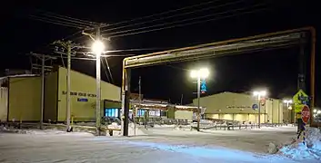 A utilidor system is used in Utqiaġvik, Alaska due to extensive permafrost underlying the city.  At right foreground is a portion of the utilidor crossing Okpik Street overhead, adjacent to Barrow High School.