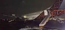 an aircraft disabled on a runway in the dark, with evacuation slides deployed