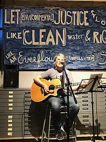 photograph of Bev Grant singing and playing the guitar