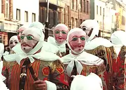 The Gilles, clad in their costumes and wax masks, wielding sticks used to ward off spirits