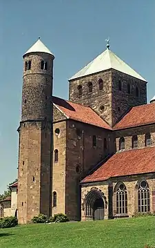 The exterior of the same church shows a short square tower with a pointed metal roof over the crossing, and a small round tower at the end of the transept.