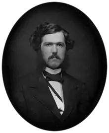 Black-and-white photograph of a young man with a mustache