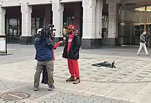 Two reporters, one with a camera, interview Smalls in front of the NLRB building, where the votes were counted.