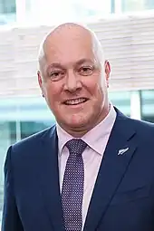 A smiling man wearing a dark business suit and tie