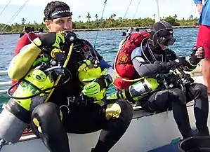 Technical divers preparing for a mixed-gas decompression dive. Note the backplate and wing setup with side mounted stage tanks.