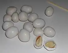 White-coated peanuts.  One has been split open to show the peanut inside.