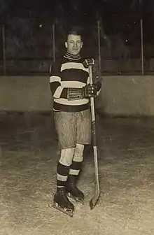 Gerard wearing skates and holding a hockey stick poses for a photo.