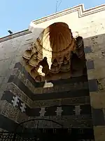 The entrance portal of the madrasa complex, composed of different coloured stone (ablaq), Arabic inscriptions, and a muqarnas canopy.