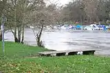 View across the river from the Ham side, showing the wooden jetty and the private boats moored at the boathouse on the north bank