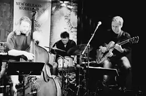 Roger Johansen (drums) live at "Herr Nilsen" (2007), flanked by Hans Mathisen (guitar) to the right and Per Mathisen (bass) to the left.