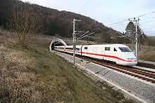 White electric train with red cheatline emerging from tunnel in the countryside (from Transport)