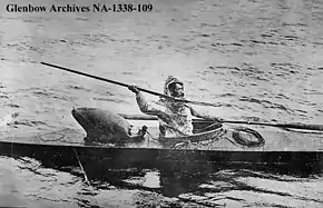 "black and white image of an Inuit hunter seated in a kayak holding a harpoon"