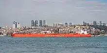 A large, low ship in front of a city skyline