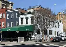 A white brick building on a corner, with a green awning reading "JR's"