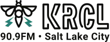 In the upper left corner, a black illustration of a bee with two teal-colored thunderbolts emerging from its wings. To the right, the letters KRCL in a sans serif in a treatment suggesting neon light tubes. Below are the words "90.9FM" and "Salt Lake City" in a sans serif in black.