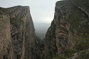 A dry valley is visible in the distance through a tall ravine