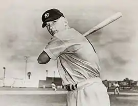 "Black and white profile photograph of a young, clean-shaven, smiling man in New York Yankees pinstripes and cap, looking slightly to his right."