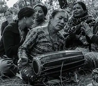 Nepalese woman playing madal in a social gathering