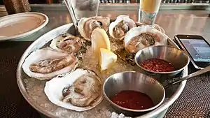 Raw oysters on the half-shell served with cocktail sauce and mignonette sauce