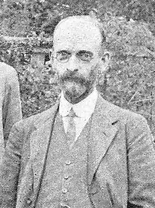 Black-and-white photographic portrait of a bearded gentleman in a suit