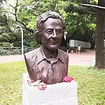 A bronze bust with flowers next to it, resting on a stone base