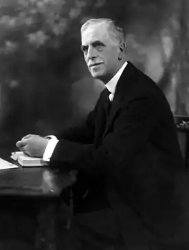 Black and white photo of man in suit sitting at table