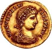 A gold coin showing the profile of a man with two strings of beads in his hair.