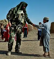 Lieutenant R. Gutierrez from A Co, 1st Bn, 7th SFG(A) gives an Afghan boy a coloring book in Kandahar Province during a meeting with local leaders, September 2008