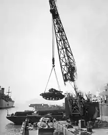 A crane hoisting a tank into a boat