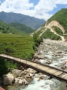 Stream flowing down a hill with a bridge crossing it